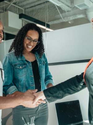 Smiling couple shaking hands with advisor in modern office.